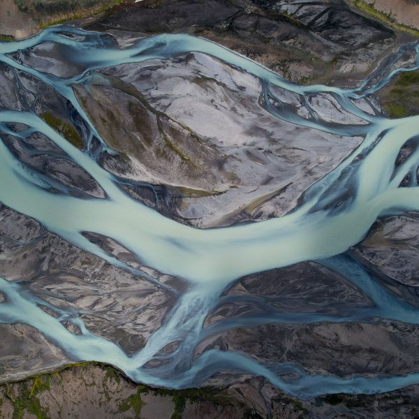 Ein Gletscherfluss teilt sich in viele Arme, aus denen ein Hauptlauf hervortritt, von oben gesehen.